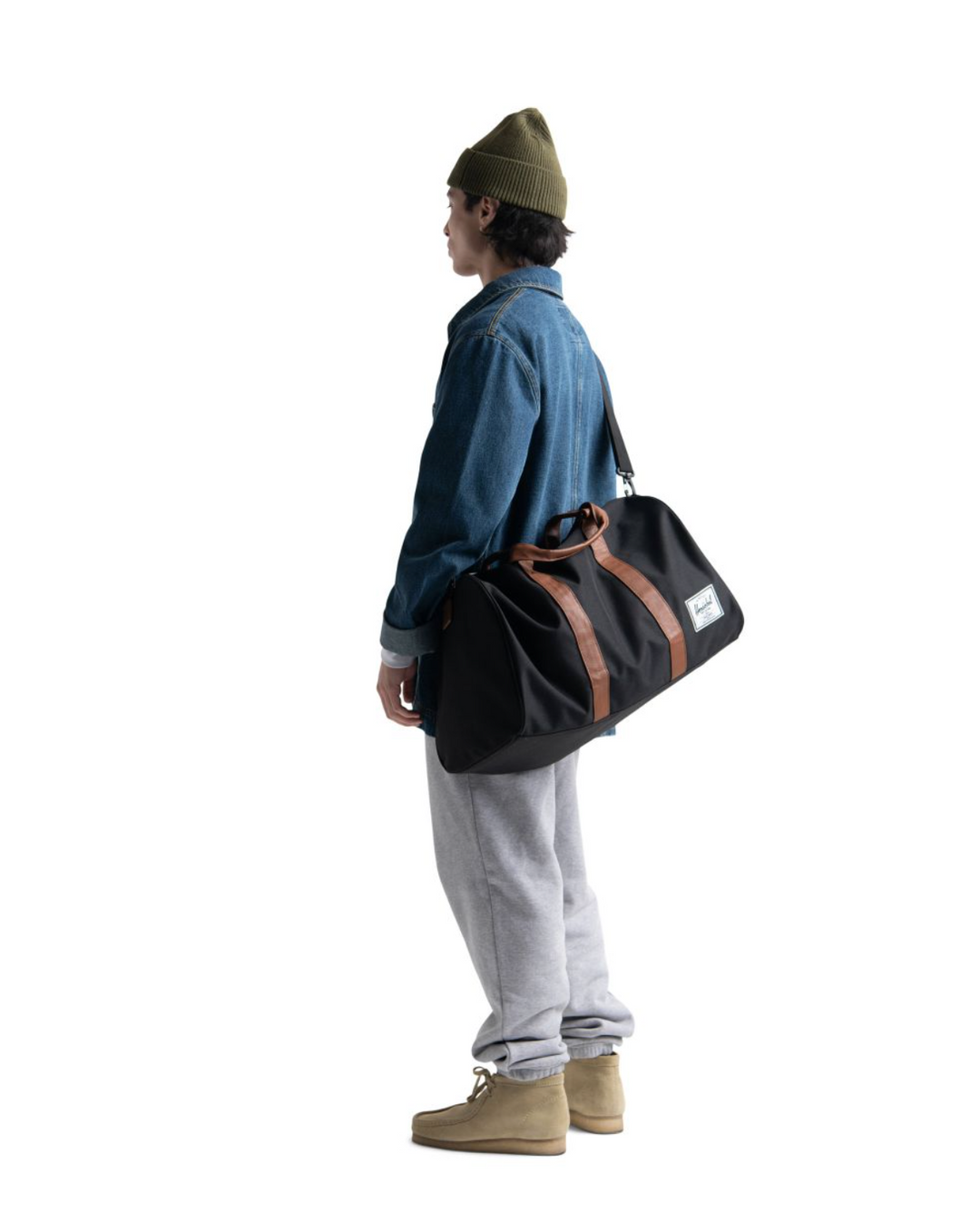 Man holding black and brown leather duffle bag
