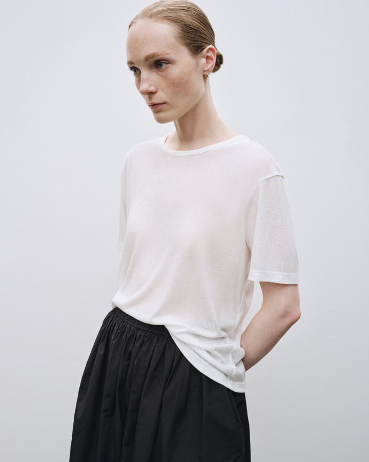 Female model wearing white tee shirt, black skirt and black sandals