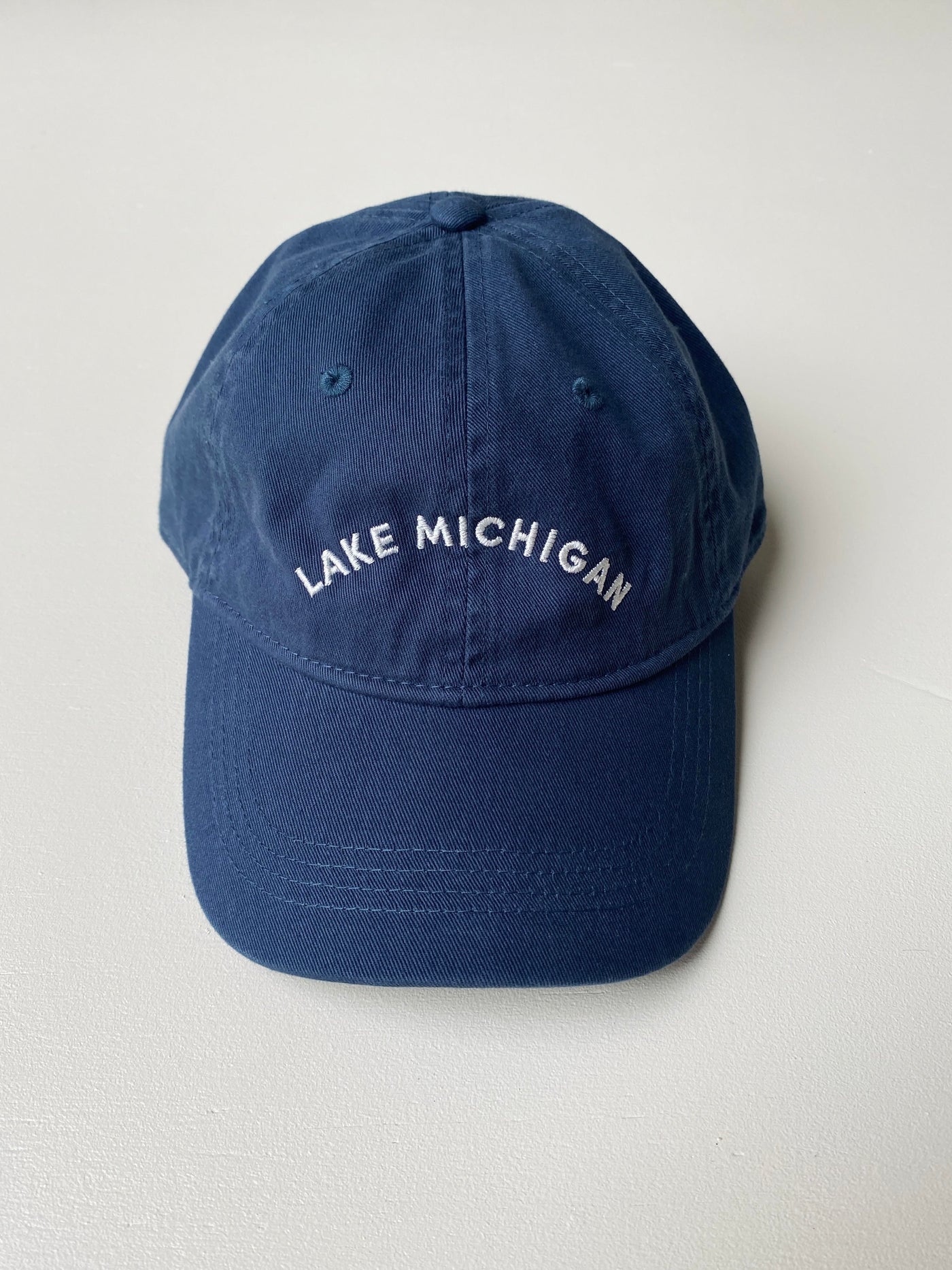 Navy baseball hat with white embroidered Lake Michigan stitched on it.